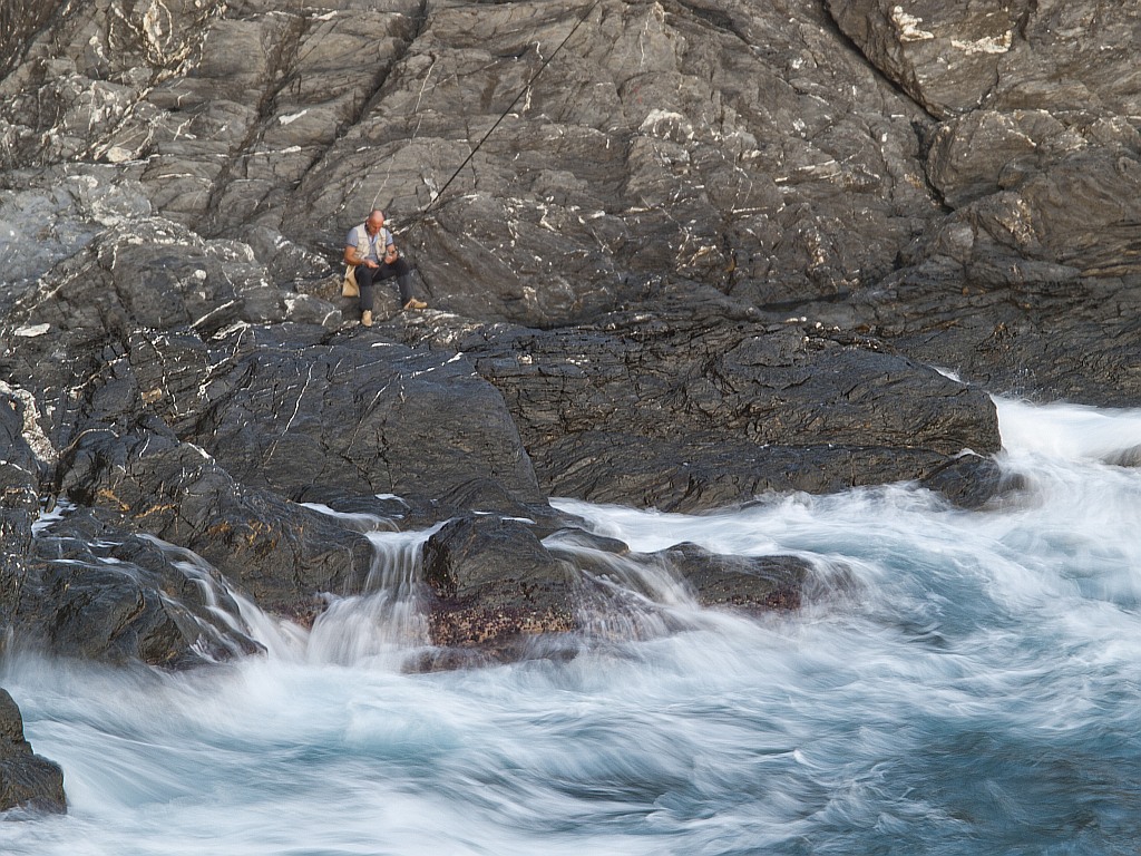 immobile il pescatore, nel fluire delle onde
