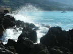 onde che si infrangono su uno scoglio del porticciolo