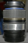 Ecco l'anello di allumino, malleabile e leggero, che ho posizionato attorno al corpo dell'ottica..., purtroppo copre alcune informazioni stampate sul barilotto..., e le didascalie sulle distanze di ripresa e diaframmi, ma che comunque non consulto mai... Si intravede anche una Oring di gomma nera, non serve a nulla se non ad evitare che il metallo, se poggiato su un piano, sfreghi lo stesso e crei graffi... vi era un altra Oring al di sotto dell'anello ma si � rotta...